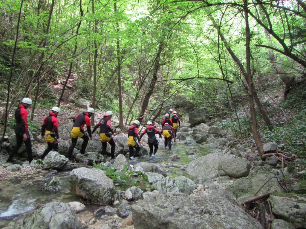 Gruppe von Personen in Neoprenanzügen beim Canyoning in der Natur.