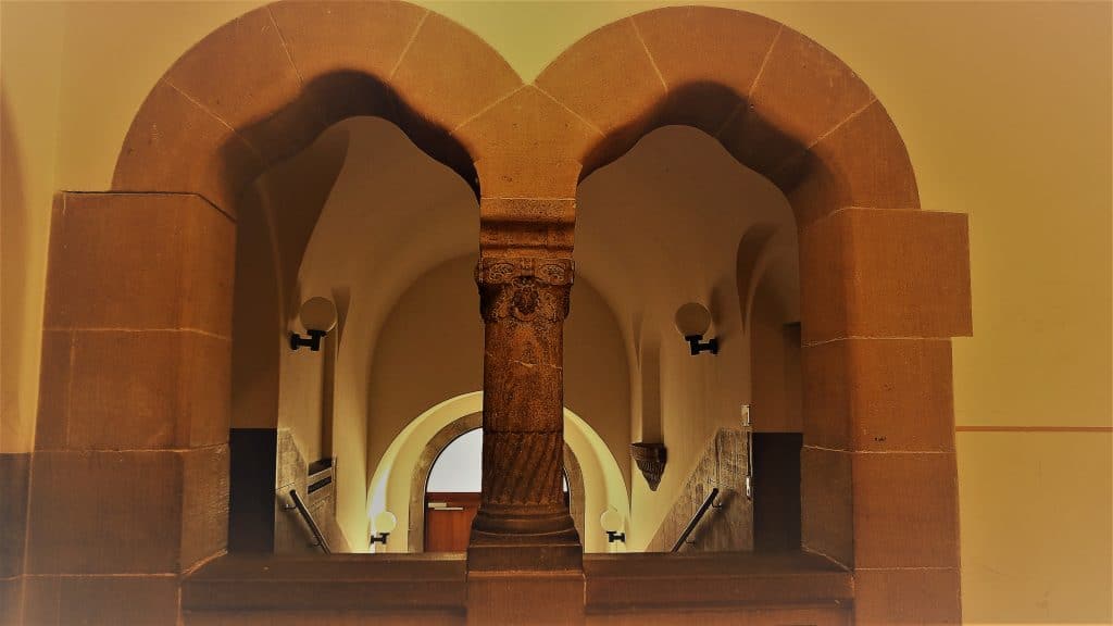 Blick durch einen historischen Bogen in ein Treppenhaus.
