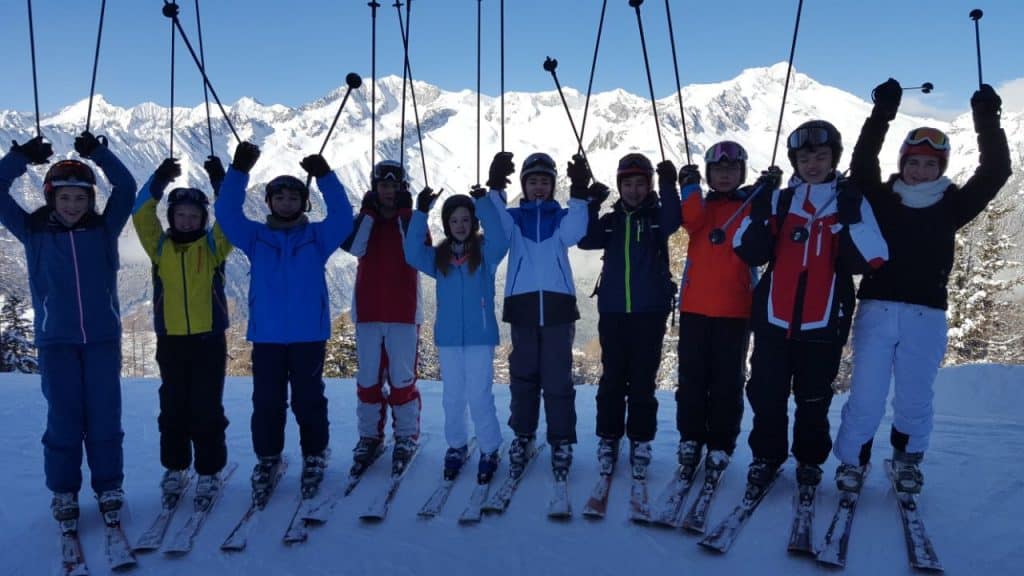 Gruppe von Skifahrern in den Alpen mit Schneebedeckten Bergen im Hintergrund.